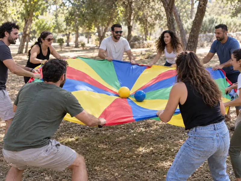 חברי צוות מפעילים יחד מצנח משחק צבעוני בפארק