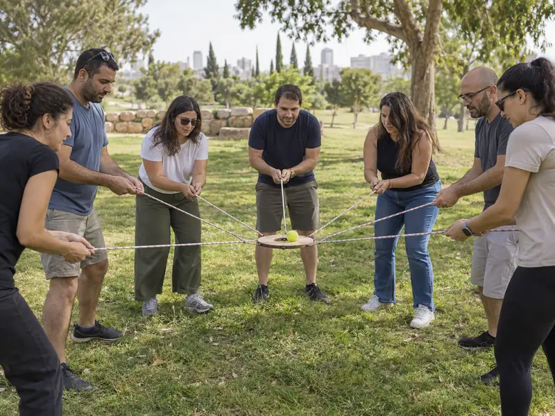 חברי צוות מכוונים יחד כדור במשחק חבלים קבוצתי